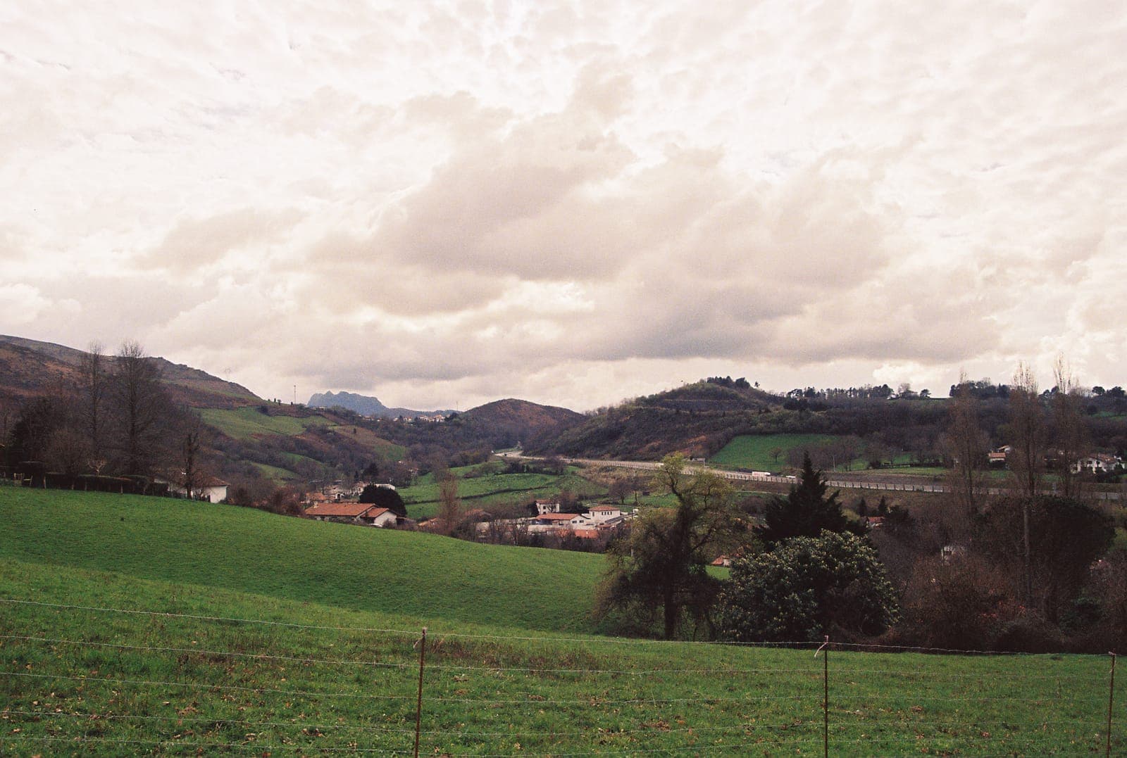 pastures and low mountains under moving clouds