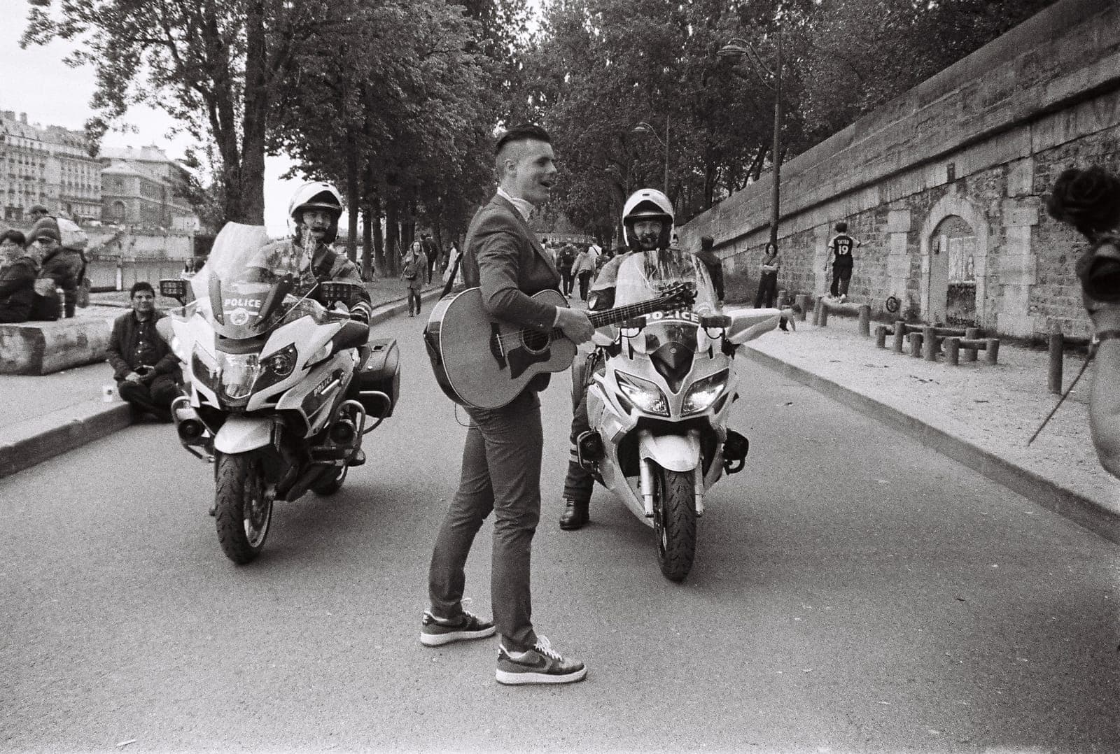 guitarist playing between two police motorcycles, in black and white